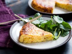 two plates with slices of quiche and greens on them, one has a fork in it