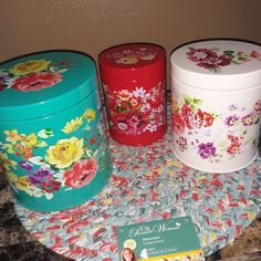 three colorful tins sitting on top of a table