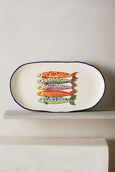 a plate with fish painted on it sitting on a shelf