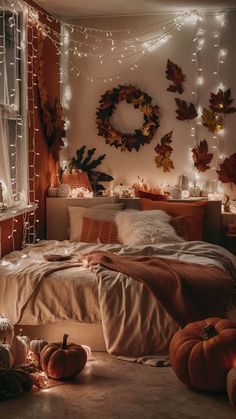 a bedroom decorated for fall with pumpkins and lights