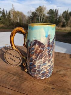 a ceramic coffee mug sitting on top of a wooden table next to a tag with an image of a turtle