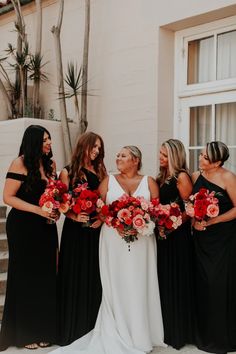 a group of women standing next to each other in front of a building with red flowers