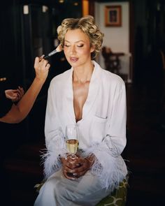 a woman is getting her make - up done by another woman in a white robe