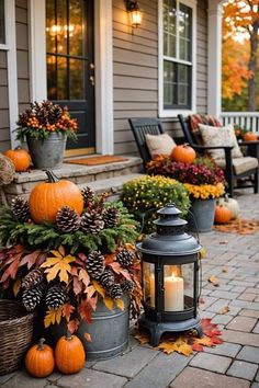 a porch decorated for fall with pumpkins and pine cones