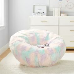 a pastel colored bean bag chair with glasses on it in front of a dresser