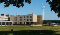 a building with wind turbines in the back ground and people sitting on benches near it