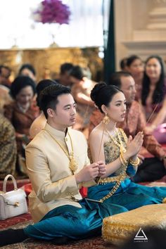 a man and woman sitting on the ground in front of other people