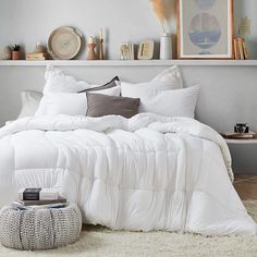 a bed with white comforter and pillows in a bedroom next to pictures on the wall