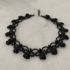 a black beaded necklace on a white surface