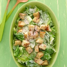 a green bowl filled with lettuce and croutons