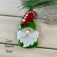 a green and white gnome ornament sitting on top of a wooden table next to a pine tree