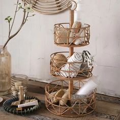 three tiered basket on the floor next to a vase with flowers and other items