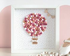 a pink and white hot air balloon in a shadow box with shoes on the floor