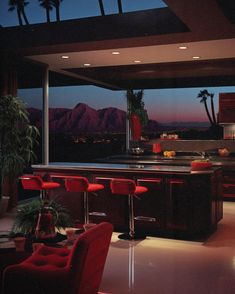 a kitchen with red chairs and an island in front of a large window at night