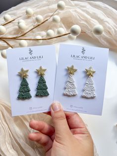 two small christmas trees are being held by someone's hand