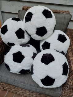 four black and white soccer balls sitting on a wicker chair