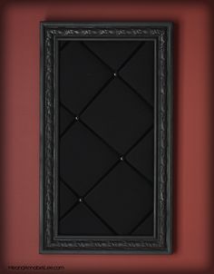 a black frame hanging on the wall with red walls behind it and an orange wall in the background