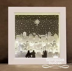 an illuminated nativity scene in a white frame