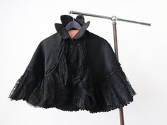 "Antique French black silk cape. Such a great shape with a high collar and wide lace trim. Main fabric is a wide ribbed silk. Fully lined. Closes with a metal hook and eye at the neck.  Measures: 15\" collar, 20 1/4\" long Great condition overall. One piece of broken lace as shown. Some light surface wear mainly to the collar. Edges of the collar are a little worn and frayed too.  Feel free to ask any questions. Ships internationally via signed for delivery." Black Capelet For Costume, Fitted Gothic Cape For Costume, Elegant Black Capelet For Costume, Elegant Black Cape For Costume, Black Fitted Capelet, Fitted Black Capelet, Formal Black Capelet, Costume Capes, Silk Cape