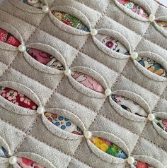 a close up of a quilt with buttons and pearls on the bottom, as well as many different designs