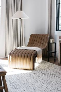 a living room with a chair, lamp and rug on the floor in front of a window