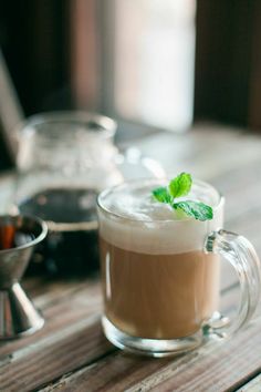 there is a glass cup with some liquid in it and a mint sprig on top