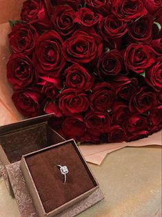 a bouquet of red roses and a ring in a box