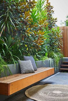 a wooden bench sitting in the middle of a garden next to a lush green wall