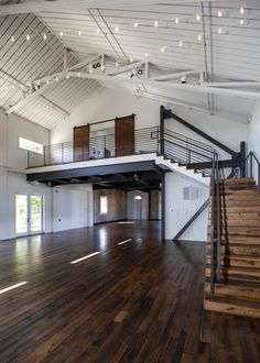 an empty room with wooden floors and stairs leading up to the second floor that has white walls