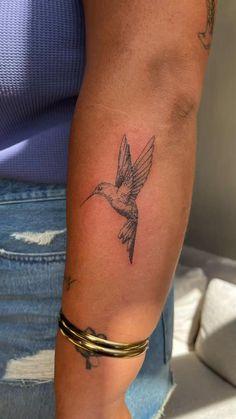 a woman's arm with a small bird tattoo on it