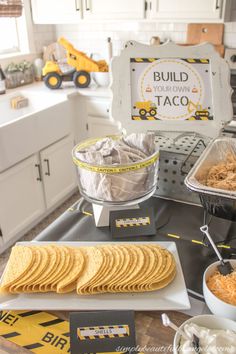 a table topped with lots of food on top of a kitchen counter next to a sign that says build taco