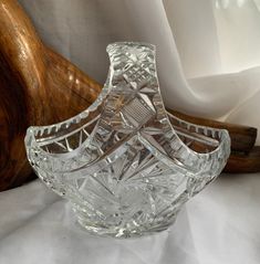 a clear glass vase sitting on top of a white table cloth next to a wooden object