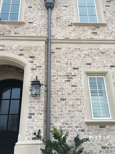 a lamp post in front of a brick building with two windows and a black door