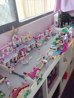 a room filled with lots of toys on top of a white shelf next to a window