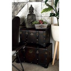 an old trunk with a buddha statue sitting on top of it next to a plant