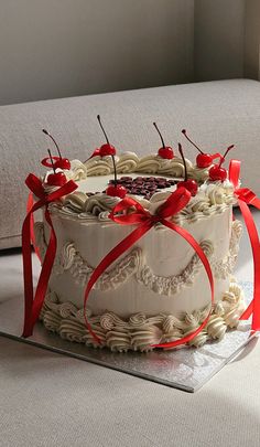 a cake with white frosting and red ribbons