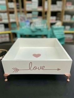 a small white box with the word love painted on it and an arrow in the middle