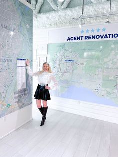 a woman standing in front of a map with her arms up and legs spread out