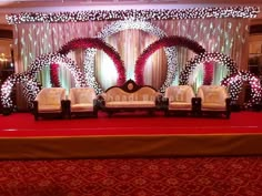 the stage is decorated with white couches and red carpeted area for an event