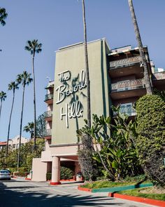 an apartment building with graffiti on the side and palm trees surrounding it in front of a parking lot