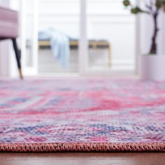 a pink rug with blue and red designs on it