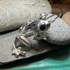 a silver frog sitting on top of a rock