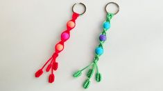 two keychains with beads on them sitting next to each other in different colors