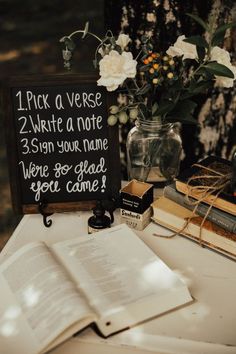 a table topped with books and flowers next to a sign that says pick a verse