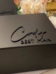 a black box with the words godly best man on it and flowers in the background