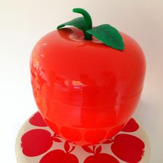 a red apple sitting on top of a white and red polka dot plate with a green leaf