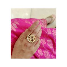 a woman's hand with a gold ring on her finger and pink saree