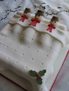 a cake decorated with frosting and decorations on top of a white sheet covered table