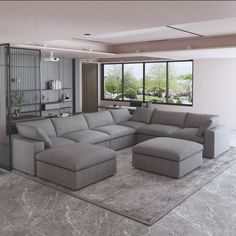 a large gray sectional couch sitting in a living room next to a tall glass window