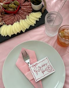 a plate with a napkin and fork on it next to a platter of food